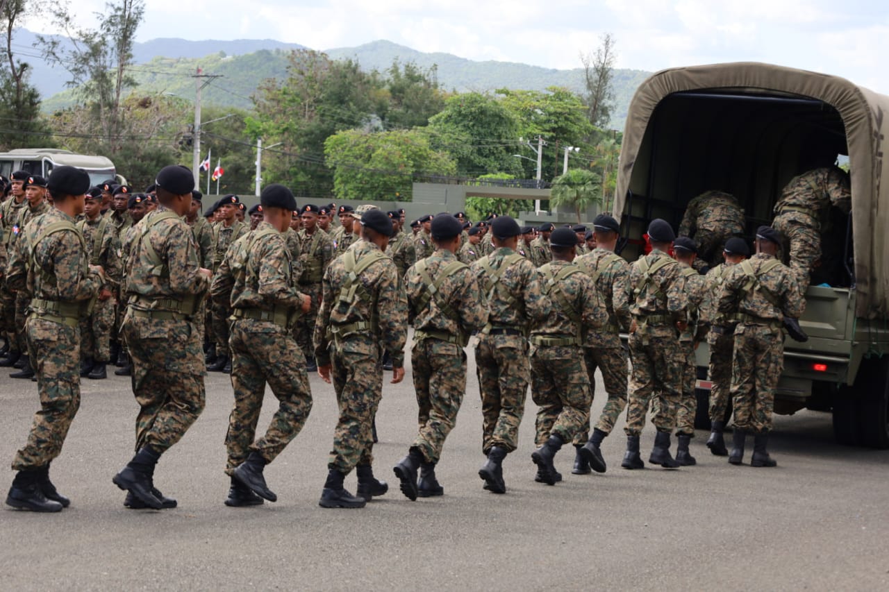 Soldados subiendo a un camión militar en formación.