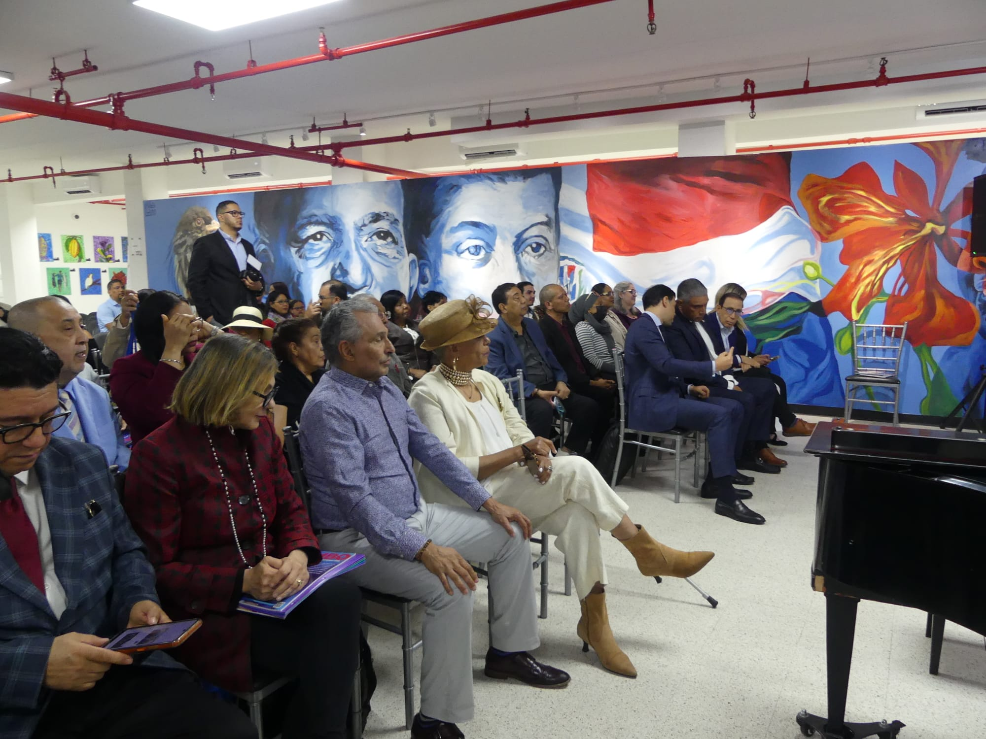 Personas en conferencia con murales coloridos de fondo.