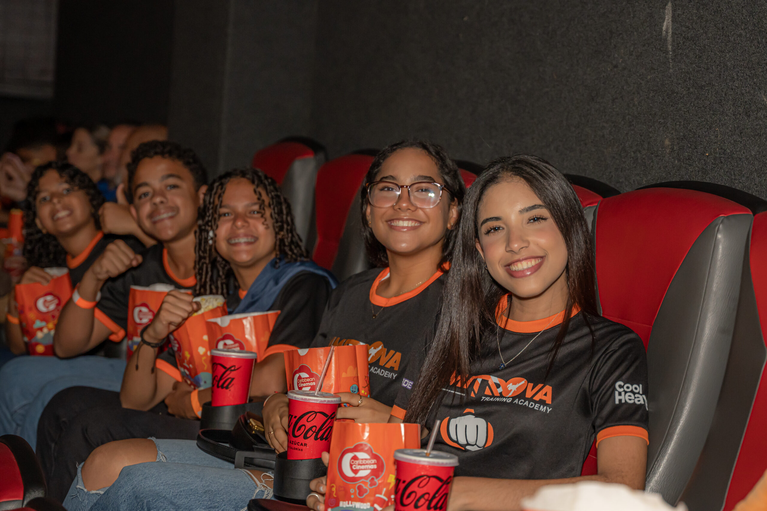 Grupo de jóvenes en cine con palomitas y refrescos.