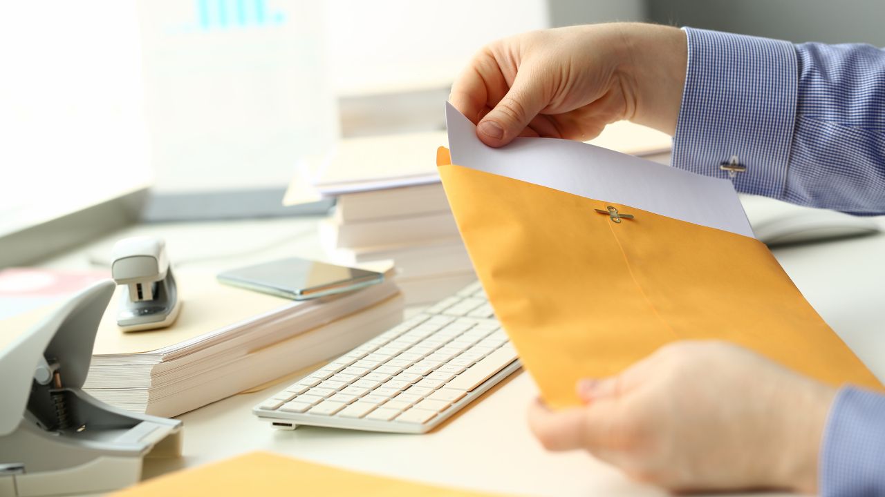Mano insertando documento en sobre marrón