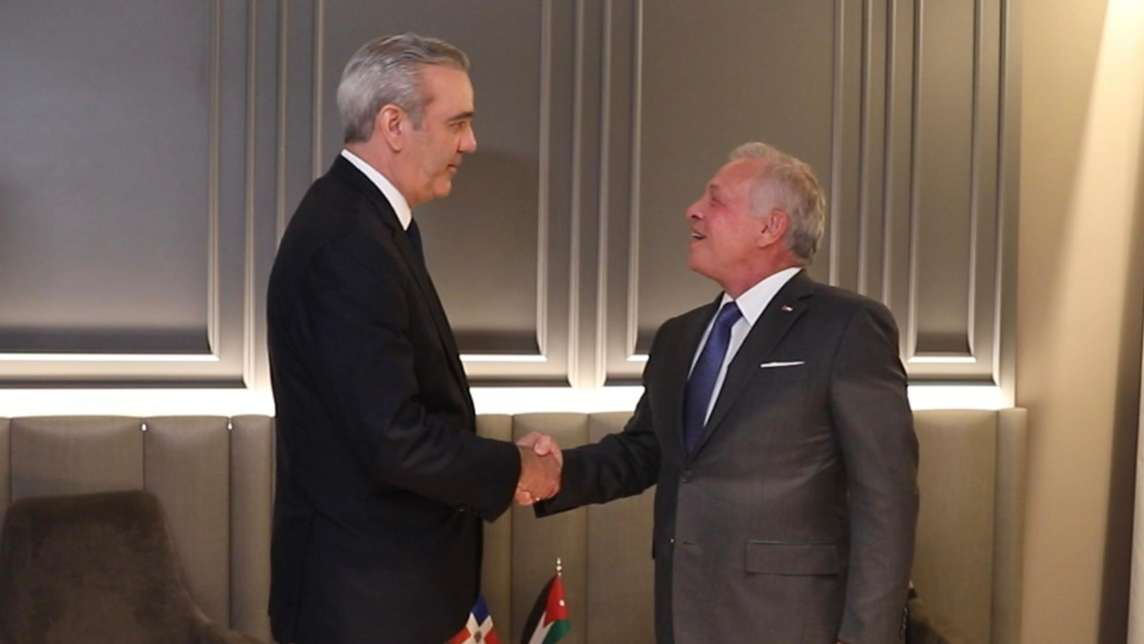 Dos hombres estrechan manos en reunión formal.