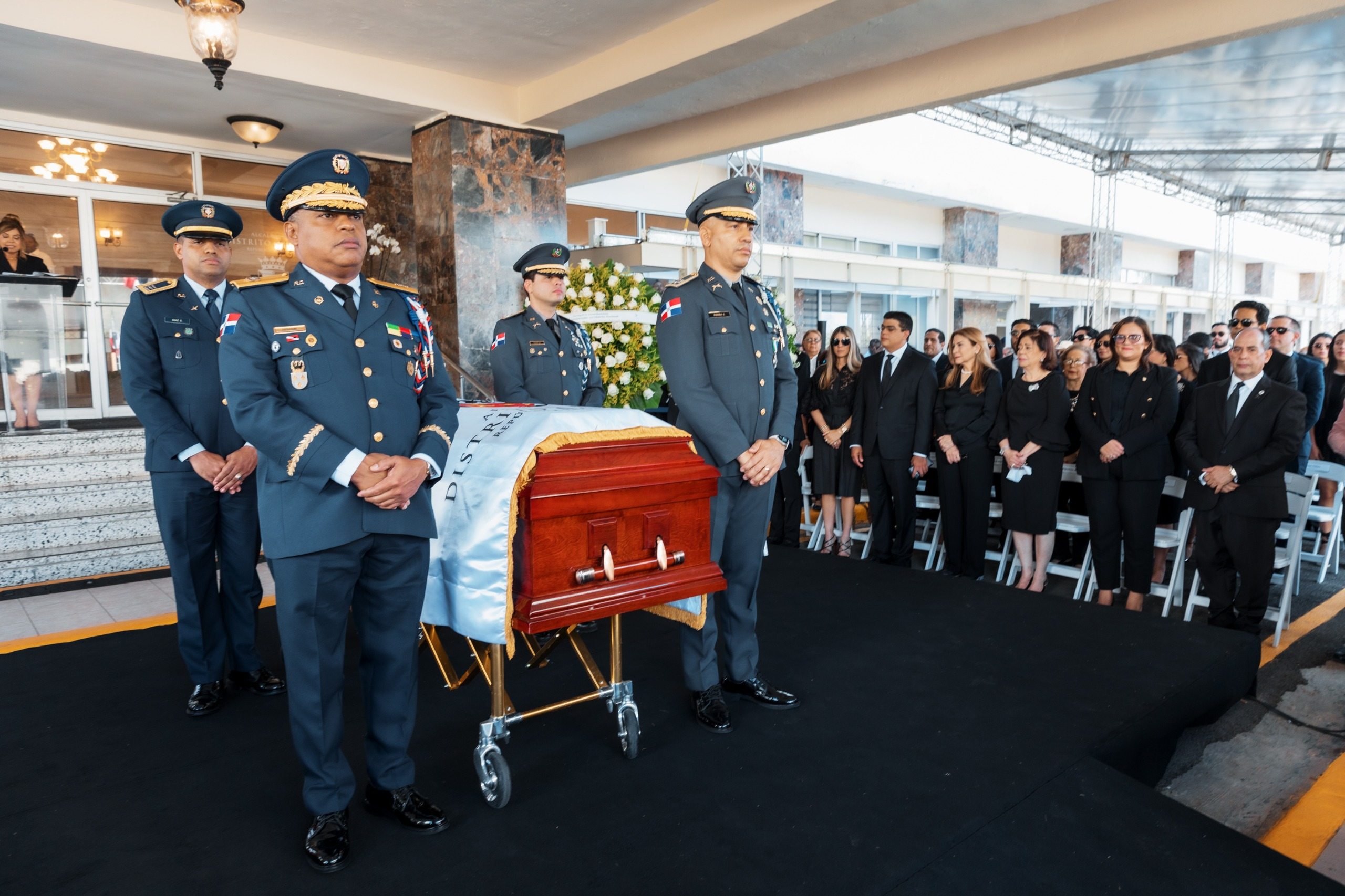 Ceremonia militar junto a un féretro cubierto.